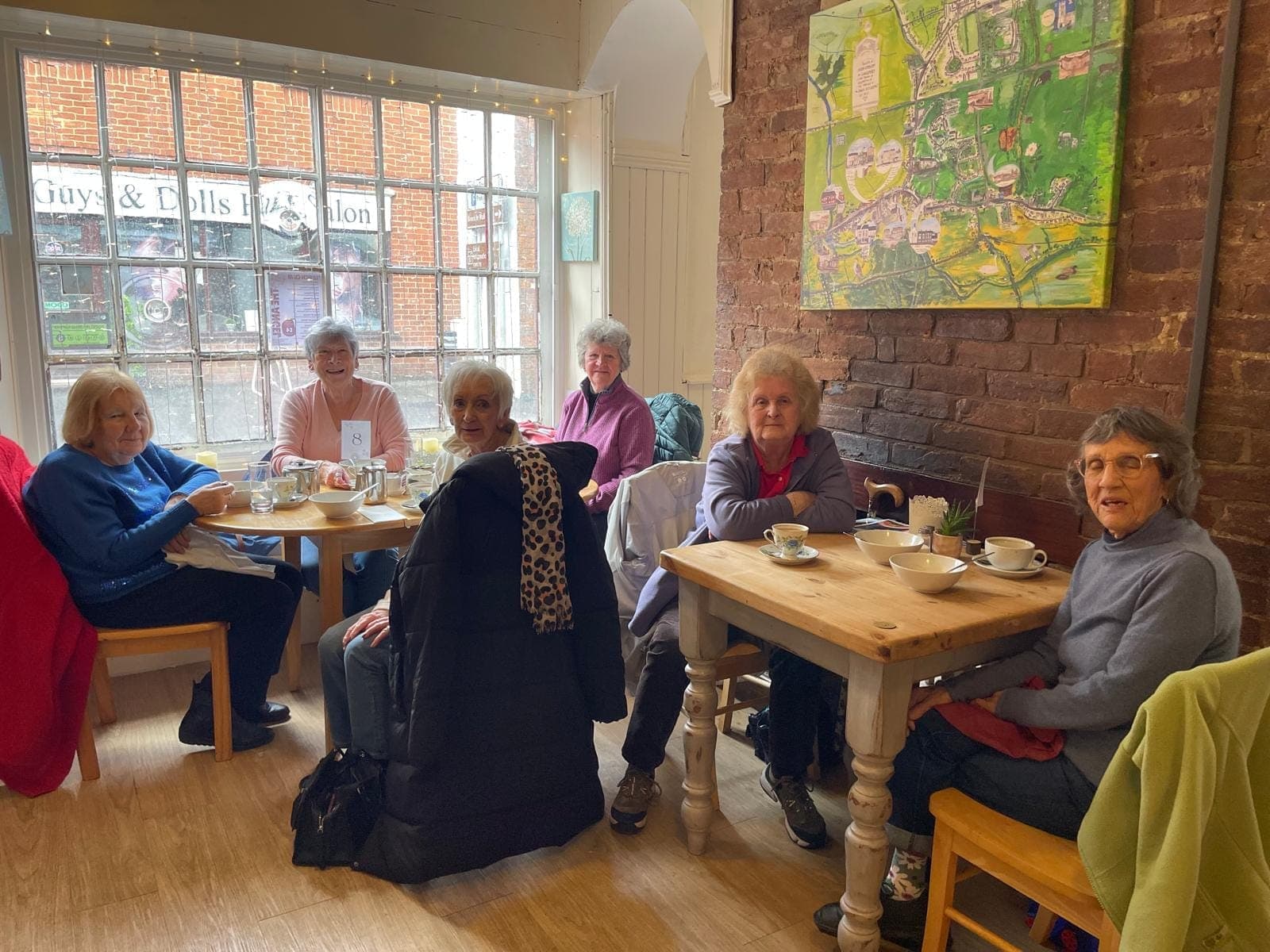 Customers sitting at wooden tables in the café by the front windows